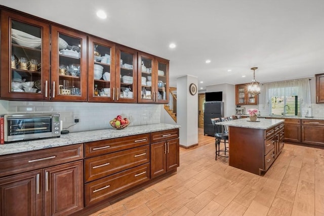 kitchen featuring a kitchen bar, tasteful backsplash, a sink, a toaster, and freestanding refrigerator