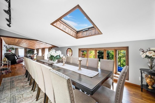 dining space featuring vaulted ceiling with skylight, plenty of natural light, and hardwood / wood-style flooring