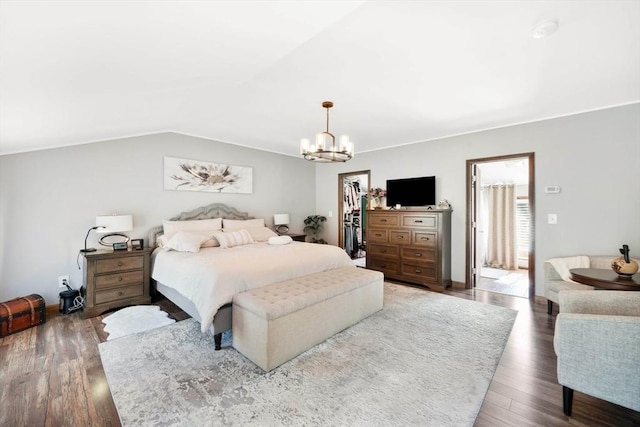 bedroom featuring an inviting chandelier, a walk in closet, wood finished floors, lofted ceiling, and a closet