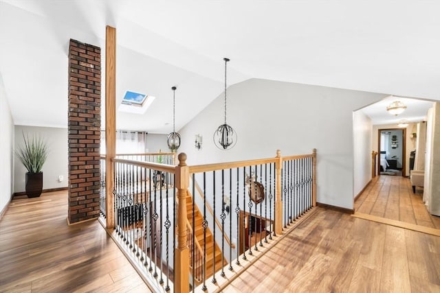 hallway with baseboards, lofted ceiling with skylight, and hardwood / wood-style floors