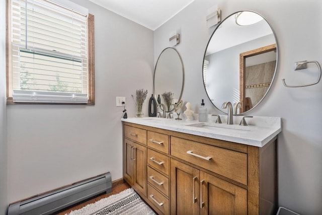 bathroom featuring a sink, a baseboard heating unit, double vanity, and wood finished floors