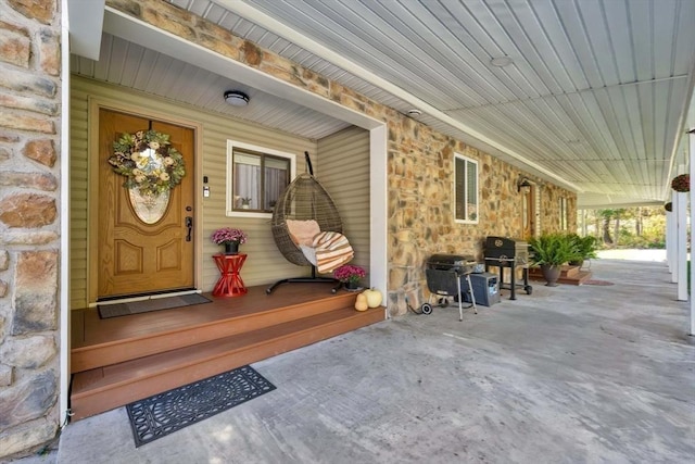 view of exterior entry with covered porch and stone siding