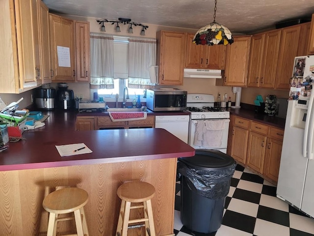 kitchen featuring decorative light fixtures, sink, white appliances, and a breakfast bar