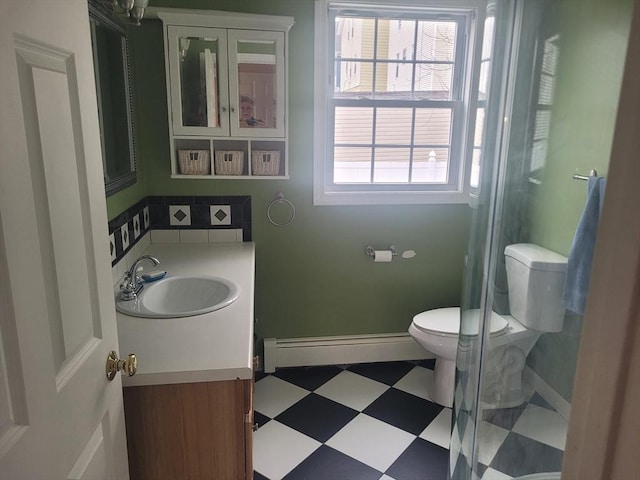 bathroom featuring baseboard heating, backsplash, vanity, a shower with shower door, and toilet