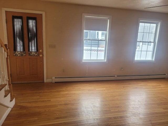 entrance foyer with a baseboard heating unit, a wealth of natural light, and light wood-type flooring