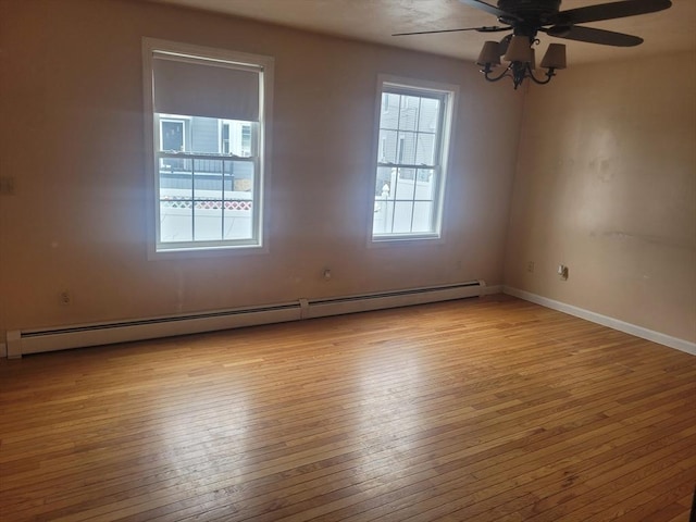 unfurnished room with a baseboard radiator, a healthy amount of sunlight, and light hardwood / wood-style flooring