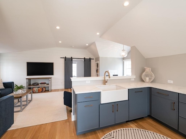 205 Powder Point Ave, Duxbury, MA 02332 - kitchen with a sink, a barn door, a peninsula, open floor plan, and light wood-style floors