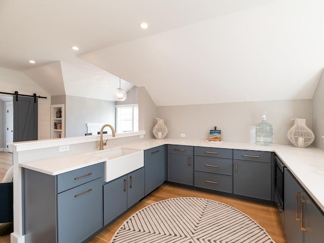 205 Powder Point Ave, Duxbury, MA 02332 - kitchen featuring vaulted ceiling, light wood-type flooring, a sink, a barn door, and a peninsula
