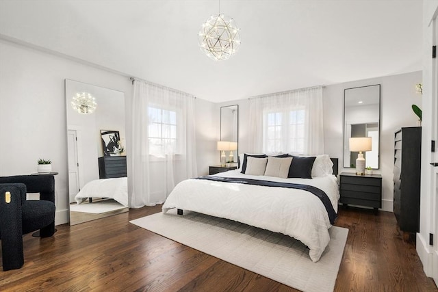 bedroom featuring multiple windows, dark wood-type flooring, and a chandelier