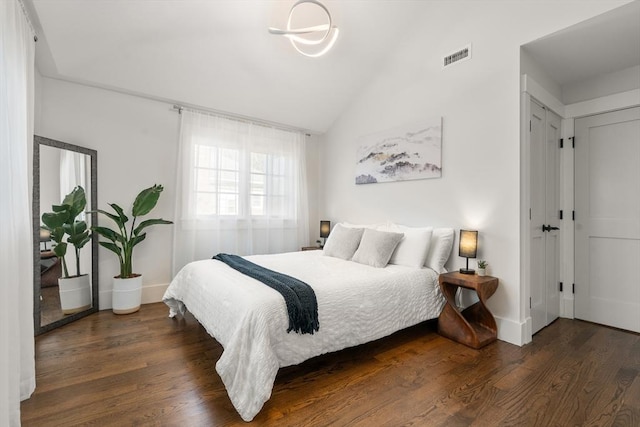 bedroom with lofted ceiling, wood finished floors, visible vents, and baseboards