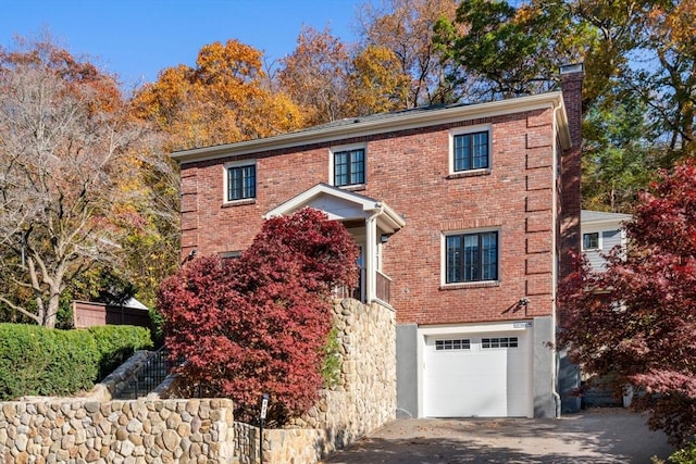 colonial house with a garage, brick siding, and a chimney