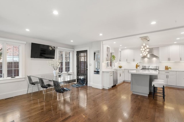 kitchen with visible vents, dark wood-type flooring, light countertops, wall chimney exhaust hood, and stainless steel dishwasher