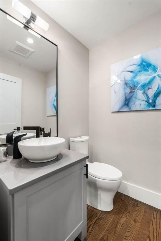 bathroom with toilet, vanity, baseboards, and wood finished floors