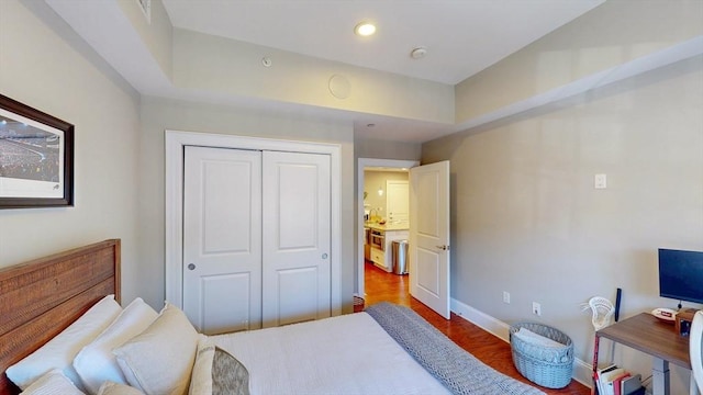bedroom with recessed lighting, baseboards, wood finished floors, and a closet