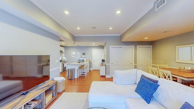 living room featuring recessed lighting, visible vents, ornamental molding, and light wood-style flooring