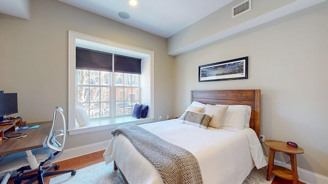 bedroom with baseboards, wood finished floors, and visible vents