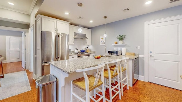 kitchen featuring white cabinets, extractor fan, freestanding refrigerator, light wood-type flooring, and visible vents