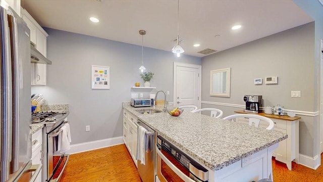kitchen featuring appliances with stainless steel finishes, a sink, a peninsula, white cabinetry, and visible vents
