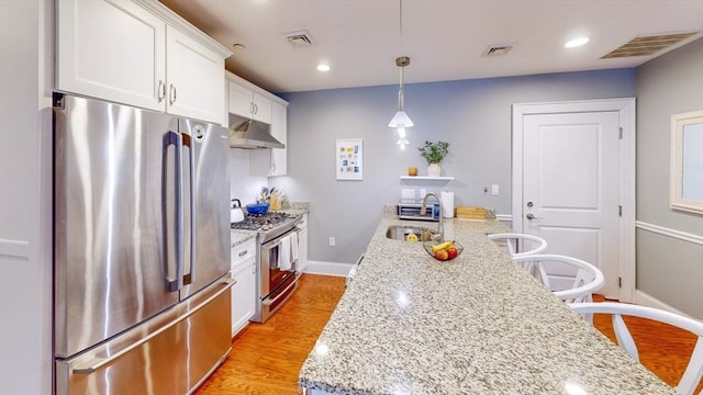 kitchen featuring visible vents, baseboards, under cabinet range hood, a sink, and appliances with stainless steel finishes