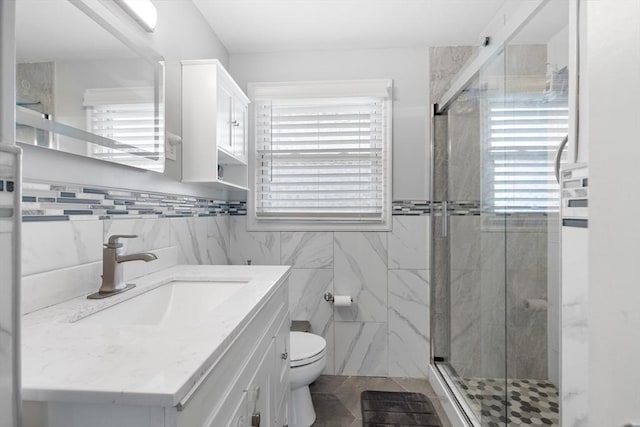 bathroom featuring an enclosed shower, vanity, toilet, and tile walls