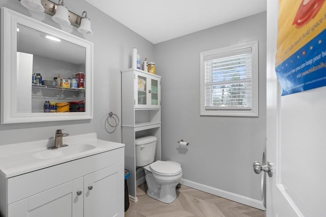 bathroom with vanity, toilet, and parquet floors