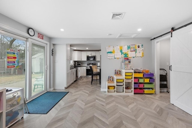 game room with a barn door, sink, and light parquet floors