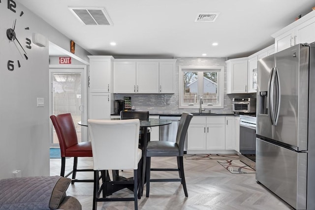 kitchen featuring stainless steel fridge, sink, white cabinets, and range