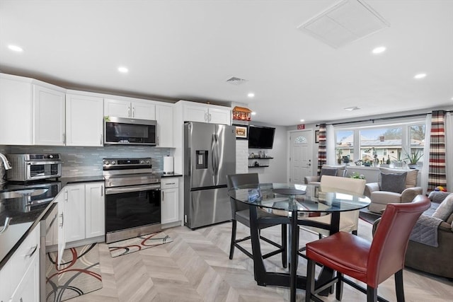 kitchen with sink, appliances with stainless steel finishes, tasteful backsplash, white cabinetry, and light parquet flooring