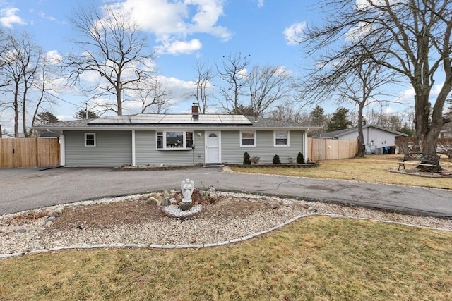 single story home with a front yard and solar panels