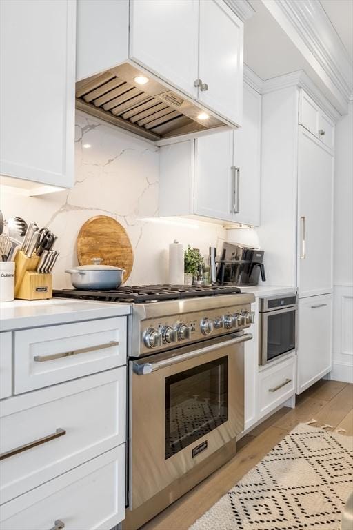 kitchen with stainless steel range, white cabinets, and light hardwood / wood-style flooring