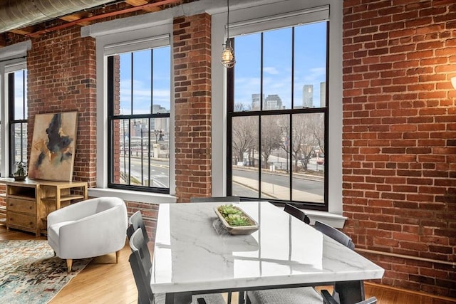 dining space with a view of city, brick wall, and wood finished floors