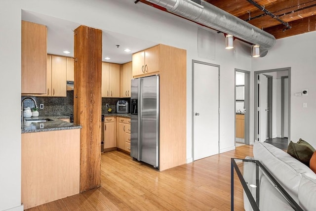 kitchen featuring light wood-style floors, stainless steel fridge, a sink, and light brown cabinetry