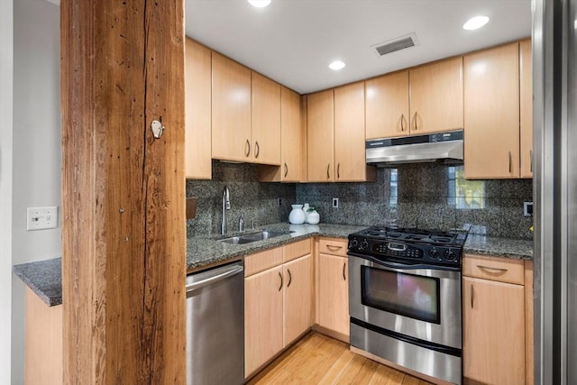 kitchen with under cabinet range hood, stainless steel appliances, a sink, visible vents, and light brown cabinetry