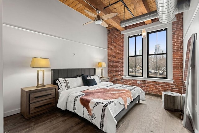 bedroom featuring wooden ceiling, brick wall, wood finished floors, and beamed ceiling