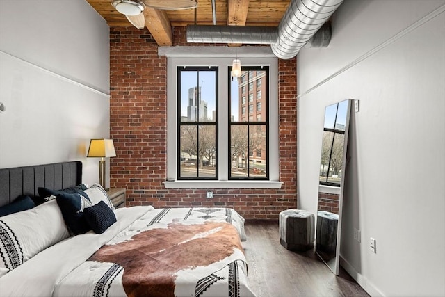 bedroom featuring wooden ceiling, brick wall, multiple windows, and wood finished floors