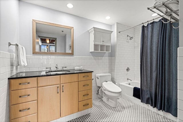 full bathroom featuring toilet, a wainscoted wall, shower / bath combination with curtain, vanity, and tile walls