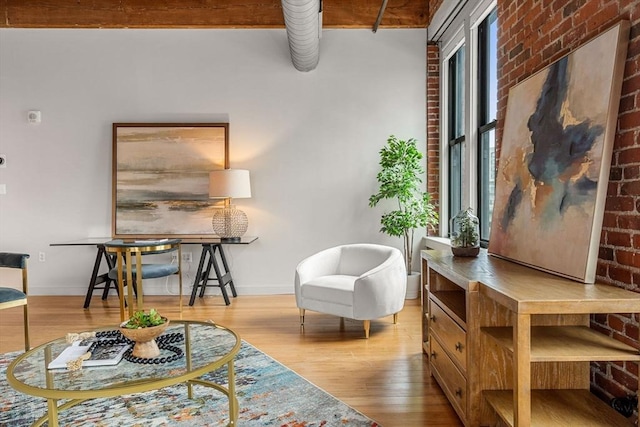 sitting room featuring brick wall, wood finished floors, and baseboards