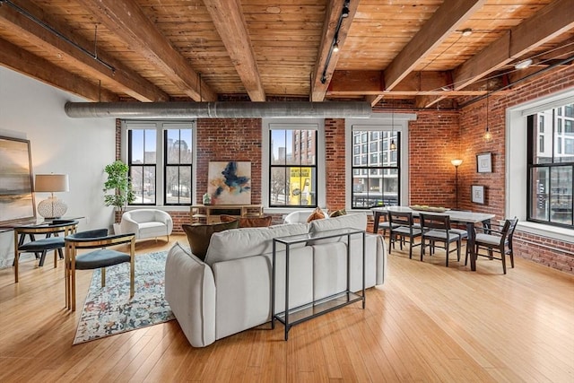 living room with light wood-style floors, beam ceiling, wooden ceiling, and brick wall