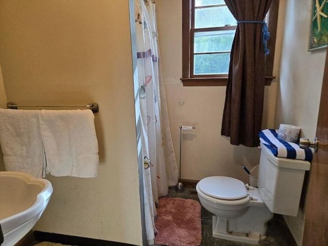 full bathroom featuring baseboards, a shower with shower curtain, toilet, and a sink