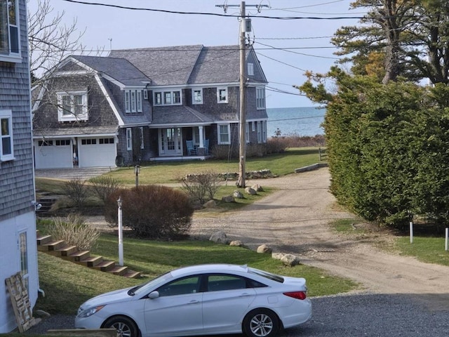 view of front of home featuring roof with shingles, dirt driveway, a front yard, and an attached garage