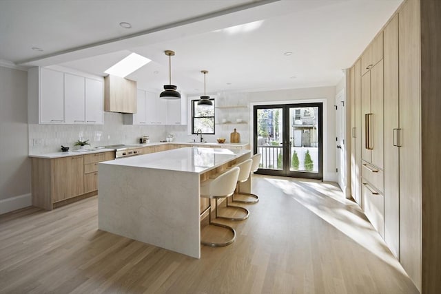 133 Fayerweather St Unit 1, Cambridge, MA 02138 - kitchen with modern cabinets, light wood-type flooring, light countertops, a kitchen island, and ornamental molding