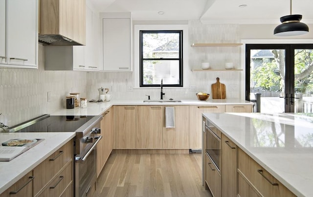 133 Fayerweather St Unit 1, Cambridge, MA 02138 - kitchen with stainless steel stove, wall chimney exhaust hood, light stone counters, light brown cabinets, and light wood-style floors