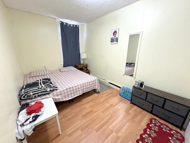 bedroom featuring a baseboard heating unit and wood finished floors