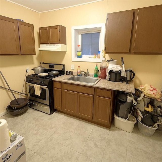 kitchen with a sink, under cabinet range hood, gas stove, and light countertops