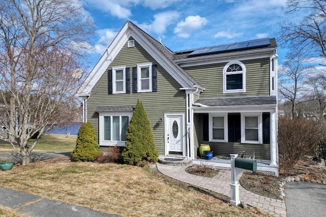 view of front facade with roof mounted solar panels and a front yard