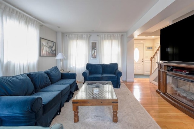 living area featuring visible vents, light wood-style floors, and stairs