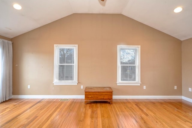 unfurnished room with vaulted ceiling, light wood-style floors, and visible vents