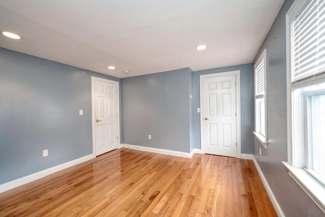 empty room featuring recessed lighting, baseboards, and light wood finished floors