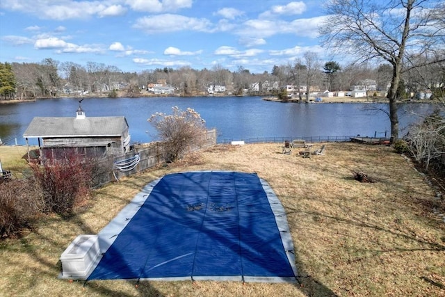 view of pool featuring an outdoor structure, a yard, fence, and a water view