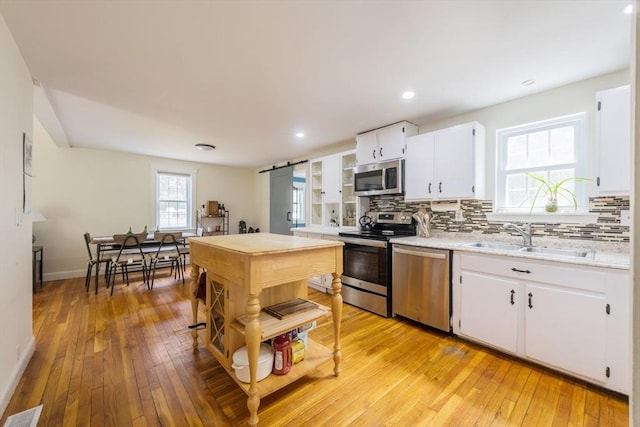 155 Great Marsh Rd, Barnstable, MA 02632 - kitchen with appliances with stainless steel finishes, a sink, backsplash, light countertops, and light wood-style floors